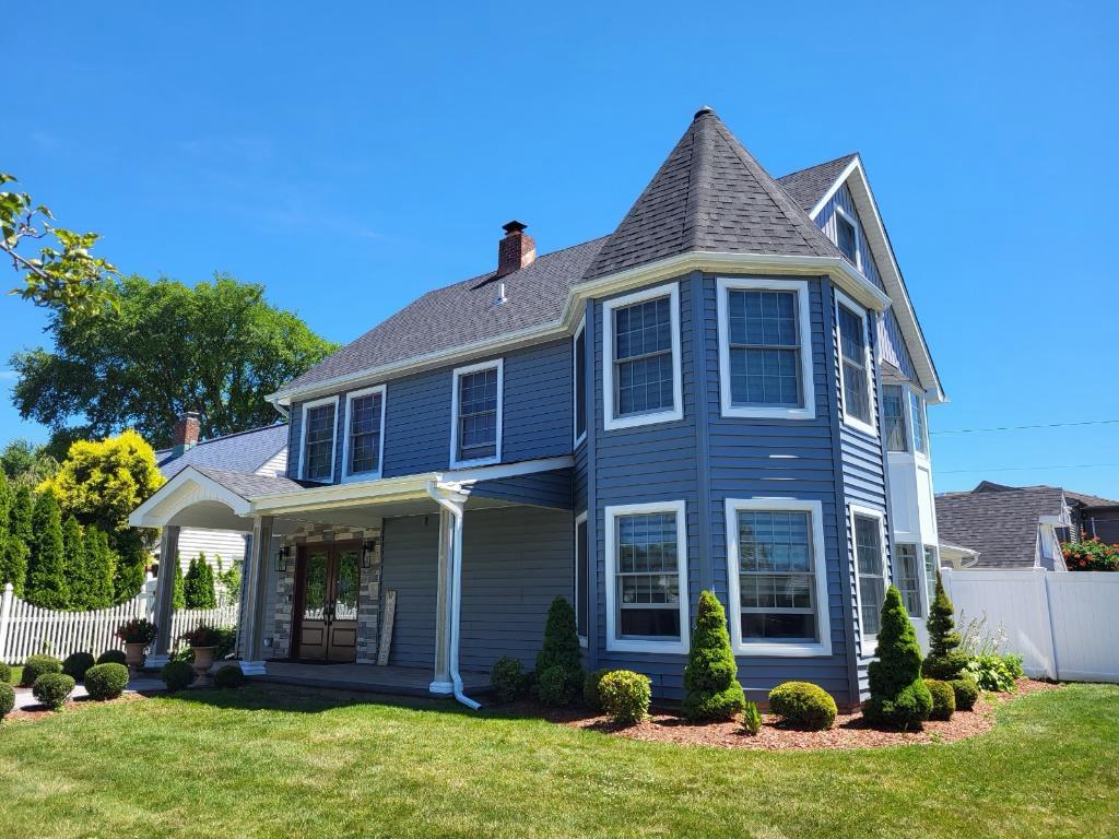 Completed gray siding, roofing, windows, and entry renovation on a two-story home